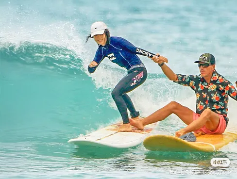 Surf instructor guiding a student while riding a wave during private water instruction in Waikiki