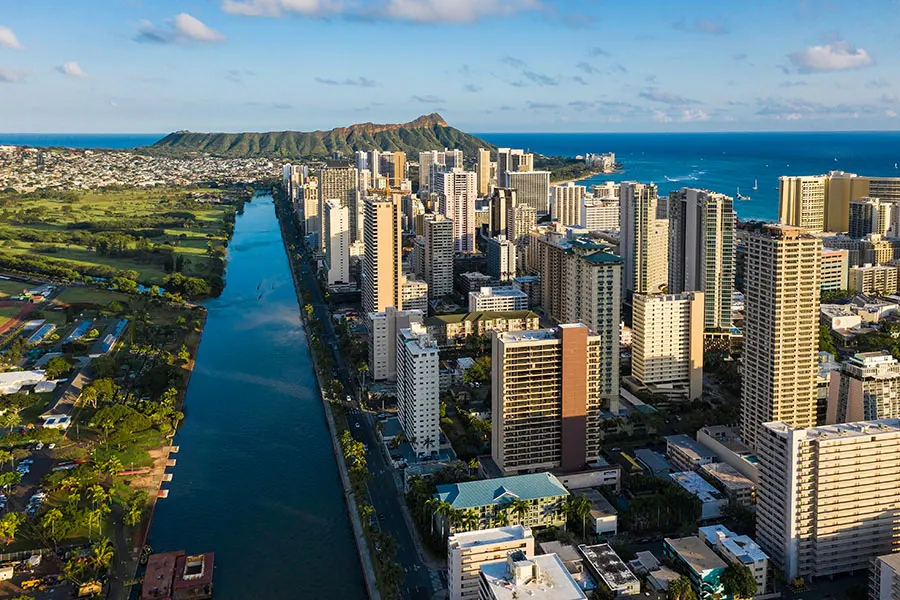Aerial view of Waikiki residential high-rise neighborhoods alongside the Ala Wai Canal and coastline.